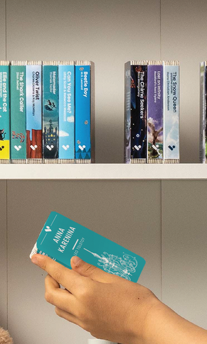 A hand taking the Anna Karenina audiobook from a shelf of Voxblock audiobooks