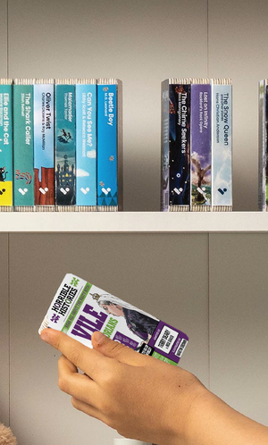 A hand taking the Horrible Histories: Vile Victorians audiobook from a shelf of Voxblock audiobooks