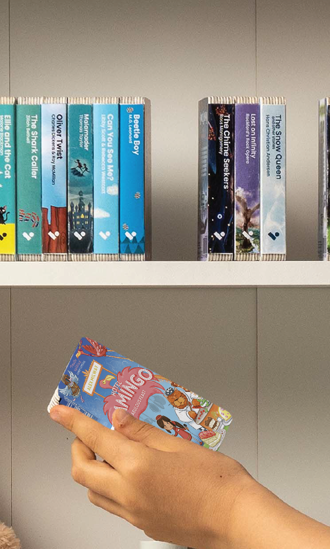 A hand taking the Hotel Flamingo: Fabulous Feast audiobook from a shelf of Voxblock audiobooks
