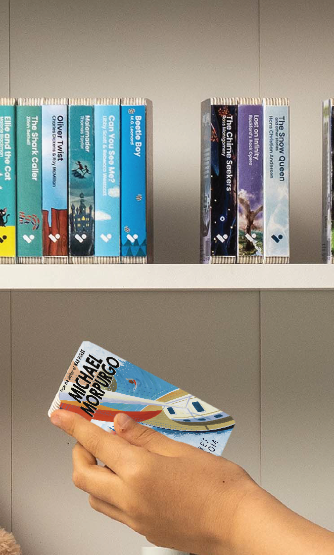 A hand taking the Kensuke's Kingdom audiobook from a shelf of Voxblock audiobooks