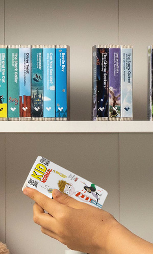 A hand taking the Kid Normal audiobook from a shelf of Voxblock audiobooks
