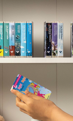 A hand taking the Magical Adventures & Magical Me audiobook from a shelf of Voxblock audiobooks