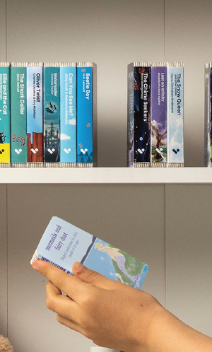 A hand taking the Mermaids & Fairy Dust audiobook from a shelf of Voxblock audiobooks
