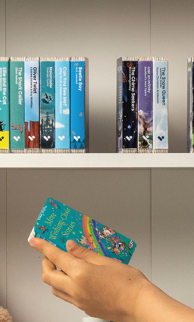 A hand taking the More Wishing Chair Stories audiobook from a shelf of Voxblock audiobooks