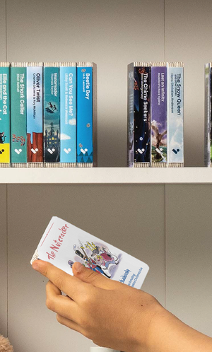 A hand taking The Nutcracker and Christmas Eve audiobook from a shelf of Voxblock audiobooks