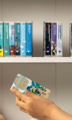 A hand taking the Of Mountains and Motors audiobook from a shelf of Voxblock audiobooks