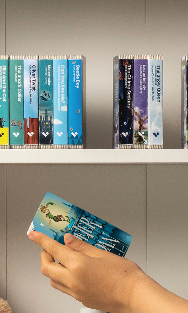 A hand taking the Peter Pan audiobook from a shelf of Voxblock audiobooks