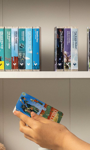 A hand taking the Pinocchio audiobook from a shelf of Voxblock audiobooks