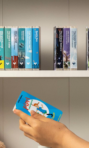 A hand taking the Pippi Longstocking Goes Aboard audiobook from a shelf of Voxblock audiobooks