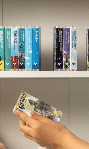 A hand taking the Pirates! audiobook from a shelf of Voxblock audiobooks