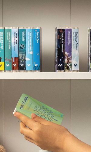 A hand taking the Rays of Calm audiobook from a shelf of Voxblock audiobooks