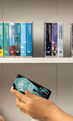 A hand taking the Simply The Quest audiobook from a shelf of Voxblock audiobooks