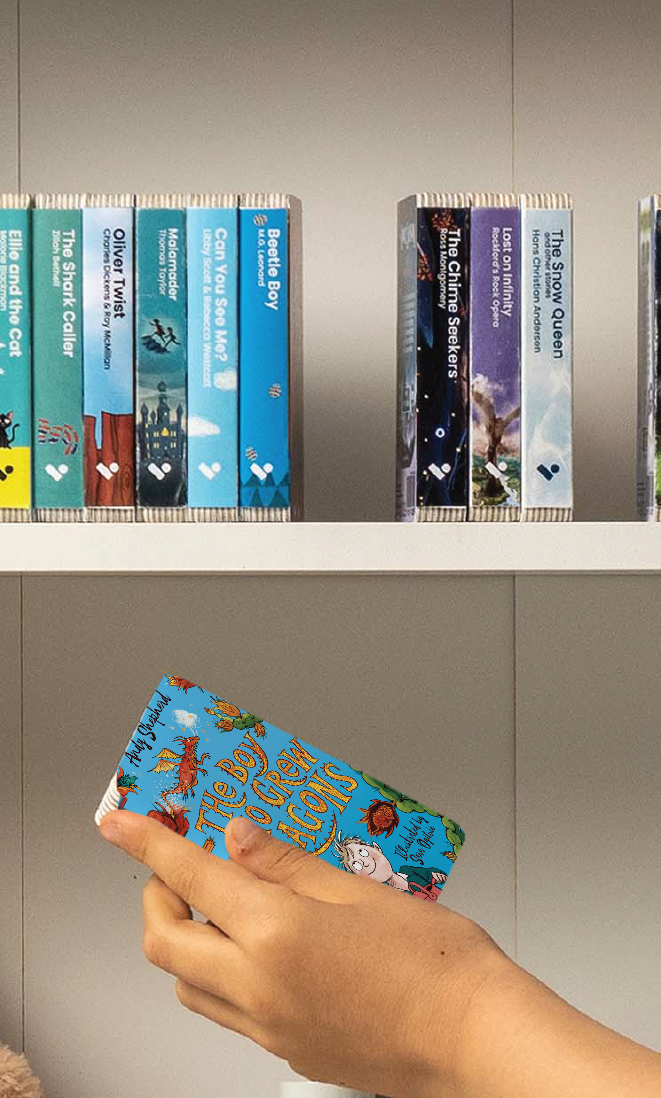 A hand taking The Boy Who Grew Dragons audiobook from a shelf of Voxblock audiobooks