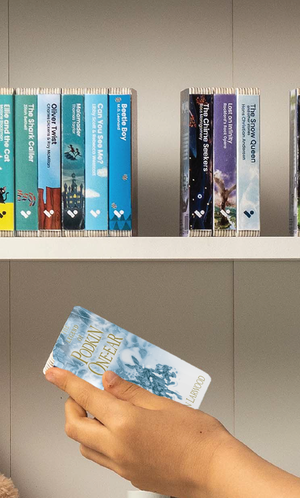 A hand taking The Five Realms: The Legend of Podkin One-Ear audiobook from a shelf of Voxblock audiobooks