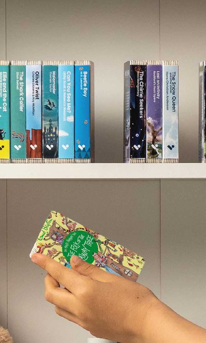 A hand taking The Folk of the Faraway Tree audiobook from a shelf of Voxblock audiobooks