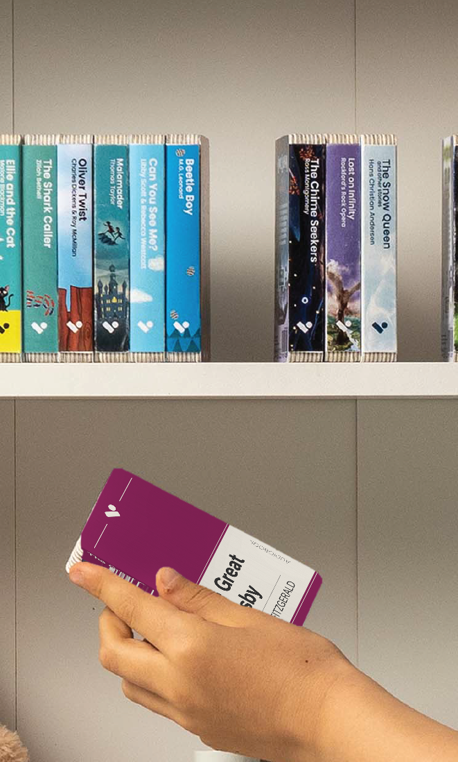 A hand taking The Great Gatsby audiobook from a shelf of Voxblock audiobooks
