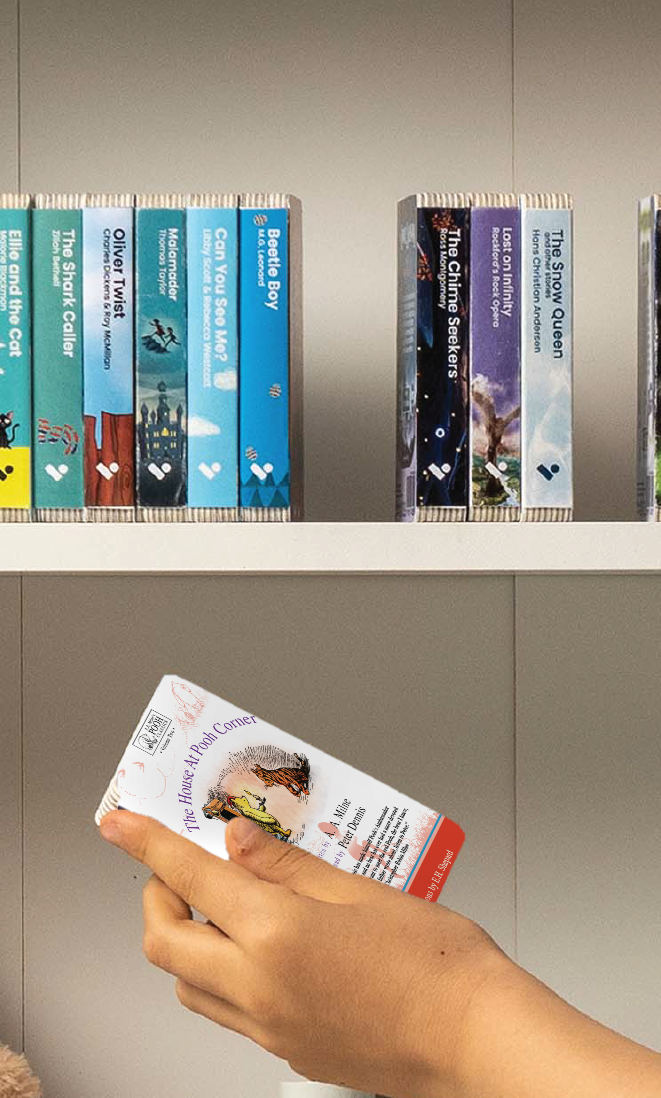 A hand taking The House At Pooh Corner audiobook from a shelf of Voxblock audiobooks