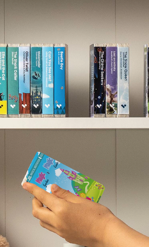 A hand taking The Magic Garden & The Magic Castle audiobook from a shelf of Voxblock audiobooks