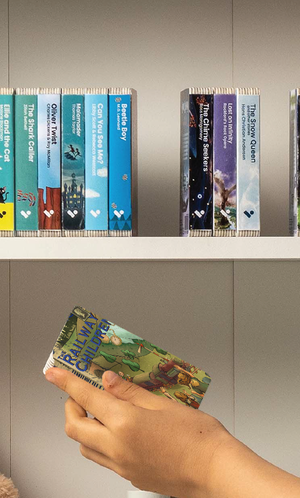 A hand taking The Railway Children audiobook from a shelf of Voxblock audiobooks