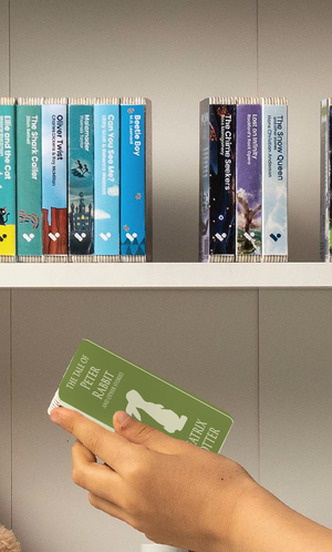 A hand taking The Tale of Peter Rabbit and Other Stories audiobook from a shelf of Voxblock audiobooks