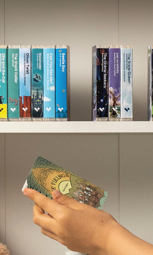 A hand taking The Vikings audiobook from a shelf of Voxblock audiobooks