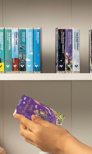 A hand taking The Wishing Chair Again audiobook from a shelf of Voxblock audiobooks