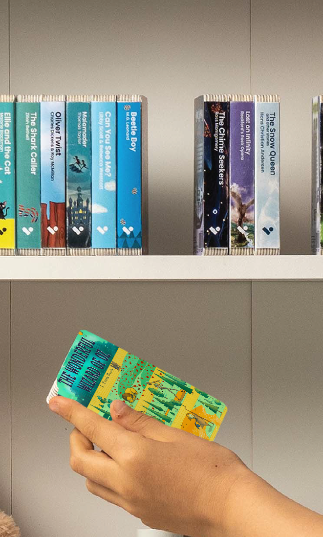 A hand taking The Wonderful Wizard of Oz audiobook from a shelf of Voxblock audiobooks