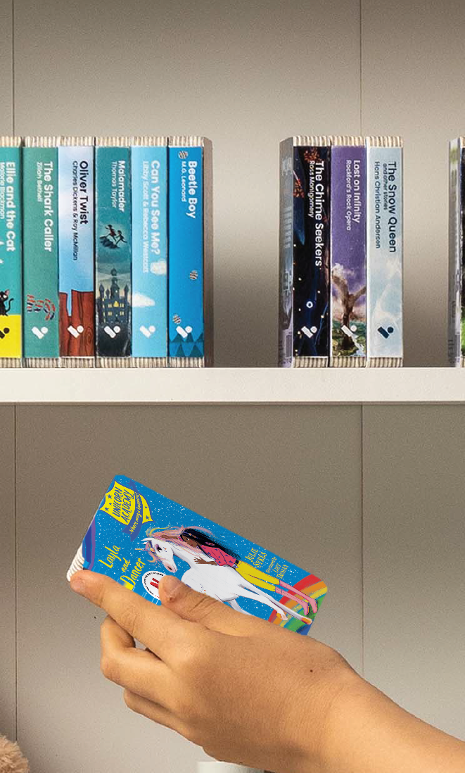 A hand taking the Unicorn Academy: Layla and Dancer audiobook from a shelf of Voxblock audiobooks