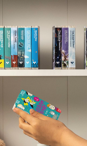 A hand taking the Wigglesbottom Primary Vol. 2 audiobook from a shelf of Voxblock audiobooks