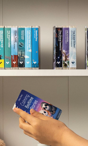 A hand taking the Zeepy Sleep Podcast audiobook from a shelf of Voxblock audiobooks