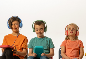 Three children wear headphones, holding Voxblock audiobook players.