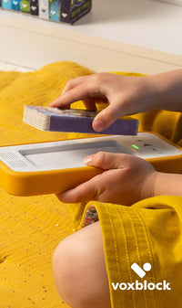 This image shows a child using a Voxblock player with a orange protective bumper.